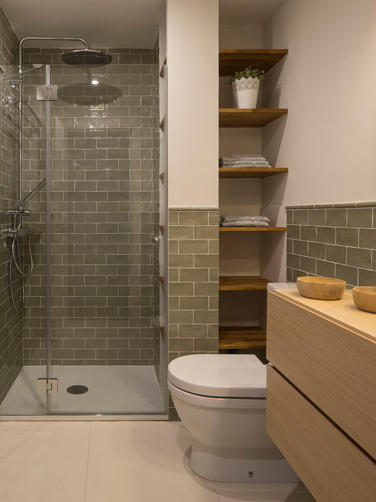 Photo of a small contemporary master wet room bathroom in Other with shaker cabinets, light wood cabinets, a one-piece toilet, green tile, ceramic tile, white walls, ceramic floors, a vessel sink, wood benchtops, beige floor and a sliding shower screen.