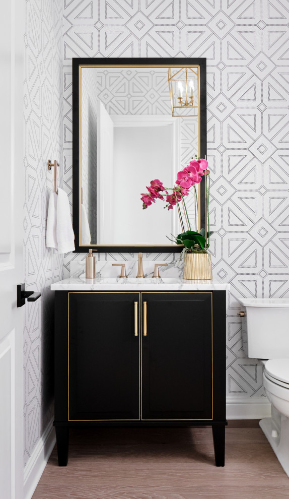 Inspiration for a mid-sized transitional black and white tile light wood floor, gray floor and wallpaper powder room remodel in Austin with furniture-like cabinets, black cabinets, a two-piece toilet, multicolored walls, an undermount sink, marble countertops, white countertops and a freestanding vanity