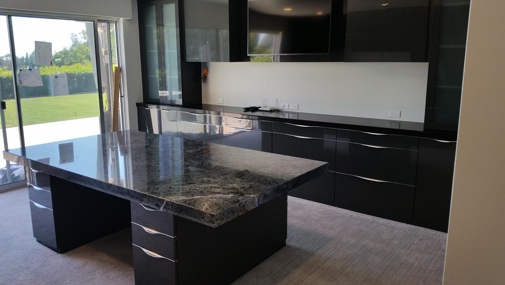 Small contemporary single-wall open plan kitchen in Los Angeles with granite benchtops, with island, flat-panel cabinets, black cabinets, carpet and grey floor.
