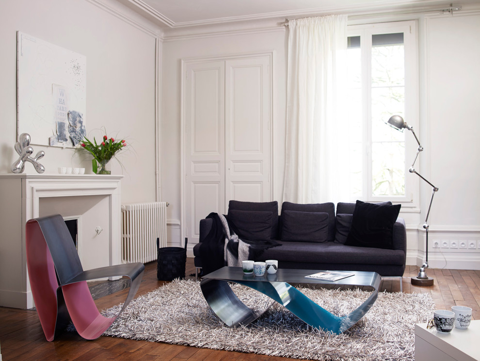 This is an example of a large contemporary enclosed living room in Angers with white walls, dark hardwood floors, a standard fireplace, a library and no tv.