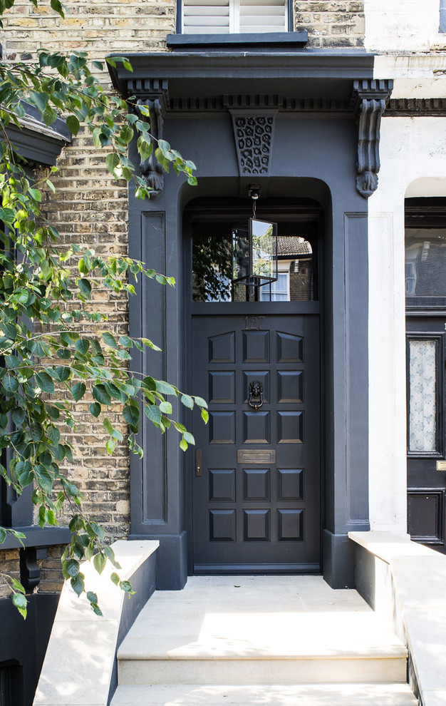 Photo of a mid-sized midcentury front door in London with grey walls, limestone floors and a single front door.