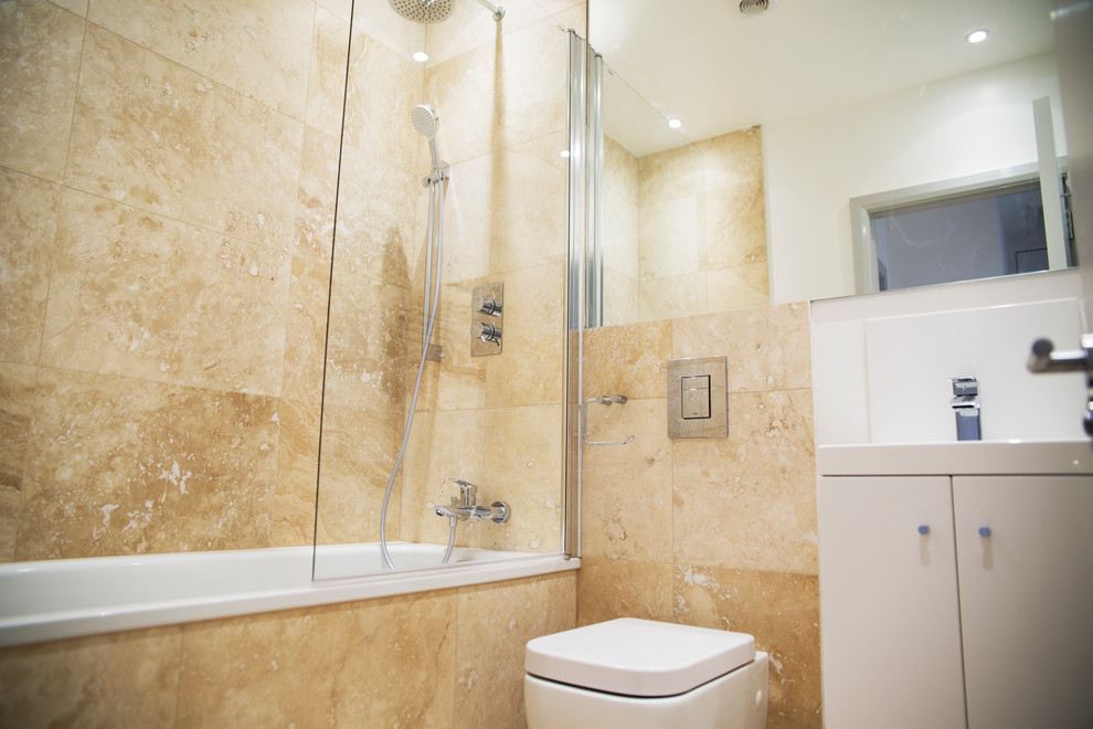 Small contemporary master bathroom in London with flat-panel cabinets, white cabinets, a drop-in tub, a shower/bathtub combo, a wall-mount toilet, beige tile, ceramic tile, beige walls, ceramic floors, a wall-mount sink, laminate benchtops, beige floor, a hinged shower door and white benchtops.