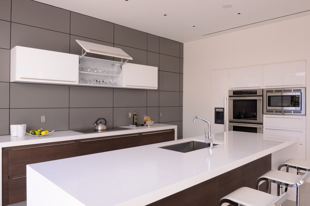 Open concept kitchen - large modern u-shaped ceramic tile open concept kitchen idea in Houston with flat-panel cabinets, white cabinets, granite countertops, gray backsplash, stainless steel appliances, white walls and an island