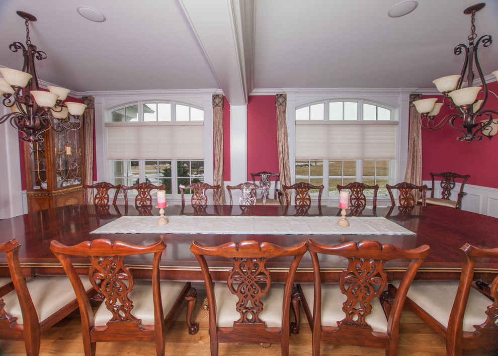 Inspiration for an expansive transitional separate dining room in Boston with red walls, medium hardwood floors, a standard fireplace, a wood fireplace surround and brown floor.