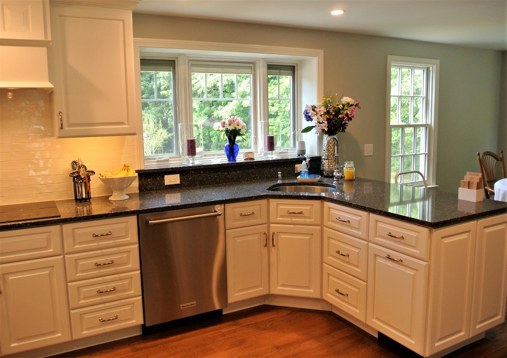 Inspiration for a transitional light wood floor eat-in kitchen remodel in Boston with an undermount sink, raised-panel cabinets, white cabinets, granite countertops, white backsplash, subway tile backsplash and stainless steel appliances