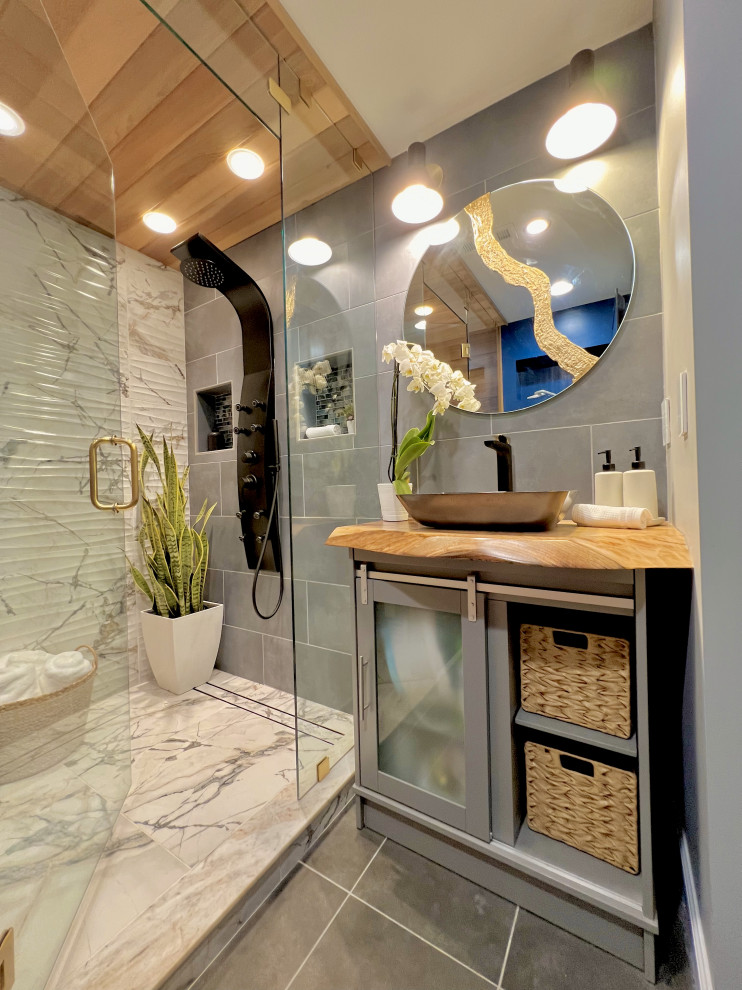 Photo of a mid-sized eclectic wet room bathroom in Atlanta with furniture-like cabinets, grey cabinets, a two-piece toilet, black and white tile, porcelain tile, blue walls, porcelain floors, with a sauna, a vessel sink, wood benchtops, grey floor, a hinged shower door, brown benchtops, a shower seat, a single vanity, a freestanding vanity, wood and wood walls.