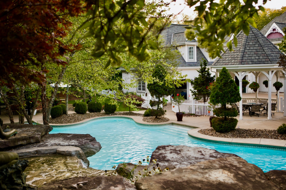 Foto de piscina tradicional grande a medida en patio trasero con paisajismo de piscina y losas de hormigón