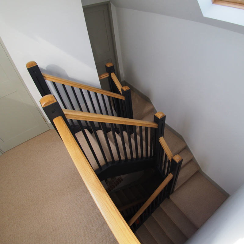 Small arts and crafts carpeted u-shaped staircase in Other with carpet risers and wood railing.