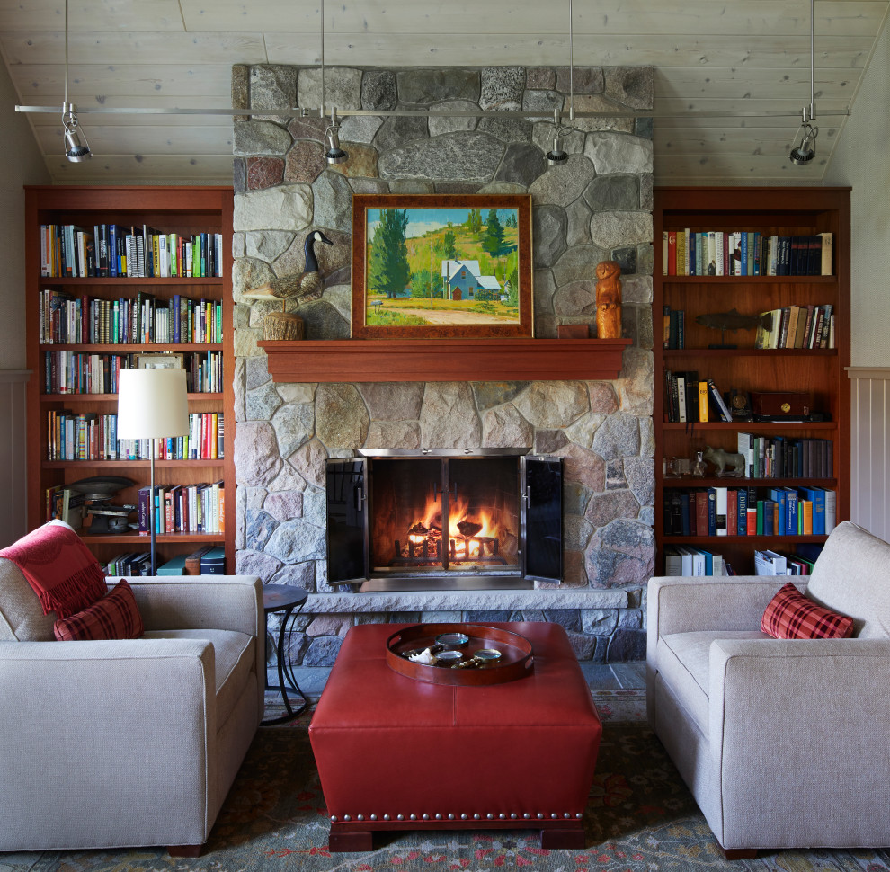 This is an example of a country open concept living room in Other with a library, beige walls, light hardwood floors, a standard fireplace, a stone fireplace surround, no tv, brown floor, vaulted and wallpaper.