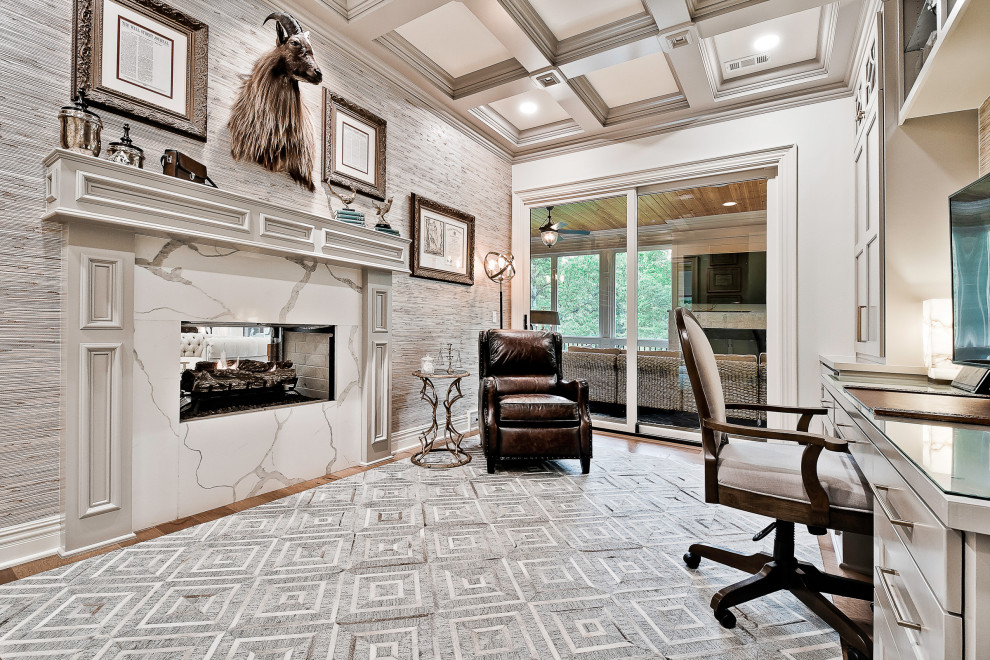 This is an example of a mid-sized transitional study room in Other with grey walls, a two-sided fireplace, a stone fireplace surround, a built-in desk, coffered and light hardwood floors.