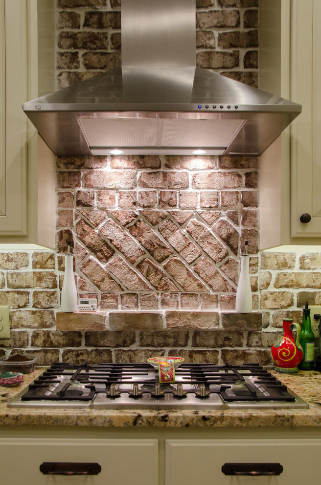 Eat-in kitchen - large transitional u-shaped medium tone wood floor eat-in kitchen idea in Raleigh with a farmhouse sink, raised-panel cabinets, beige cabinets, granite countertops, multicolored backsplash, terra-cotta backsplash, stainless steel appliances and a peninsula
