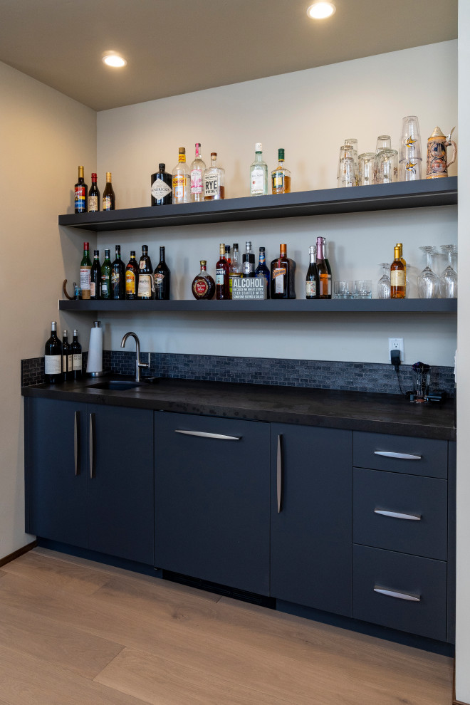 Inspiration for a mid-sized midcentury single-wall wet bar in Other with an undermount sink, flat-panel cabinets, blue cabinets, quartzite benchtops, light hardwood floors and black benchtop.