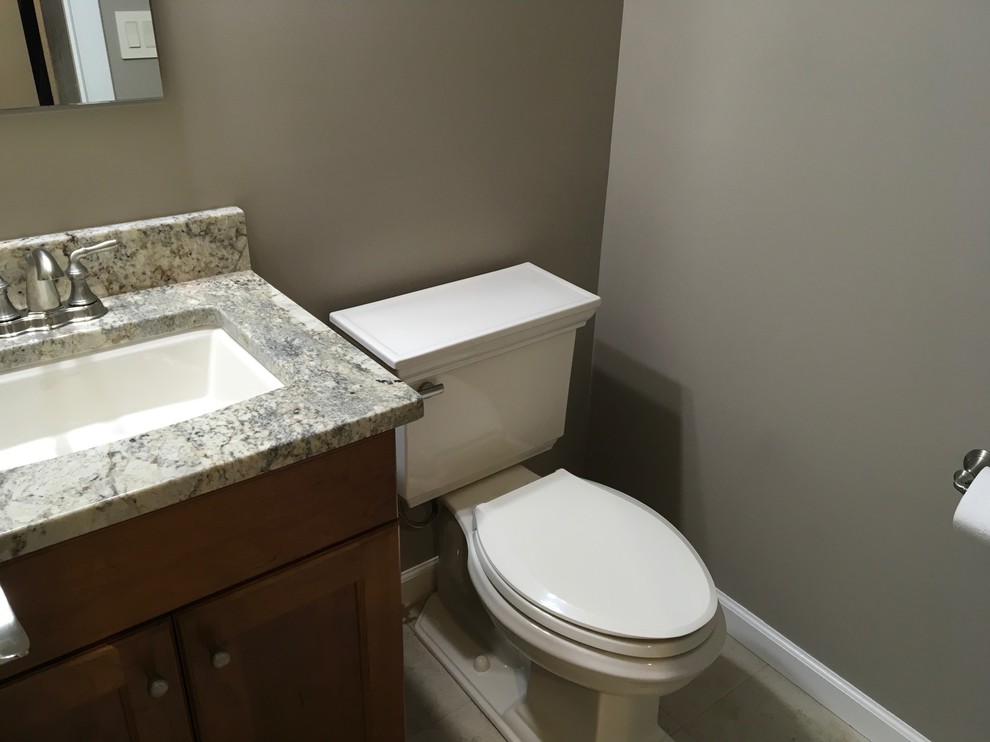 Design ideas for a traditional powder room in New York with shaker cabinets, dark wood cabinets, a two-piece toilet, beige walls, cement tiles, granite benchtops and beige floor.