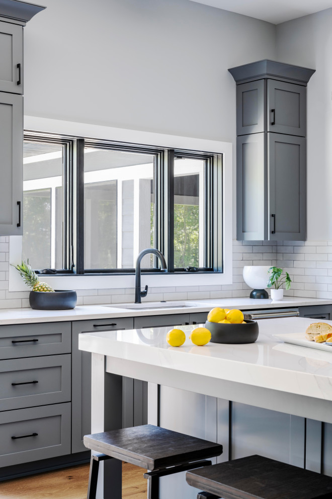 Large transitional medium tone wood floor eat-in kitchen photo in Chicago with shaker cabinets, gray cabinets, white backsplash, ceramic backsplash and an island