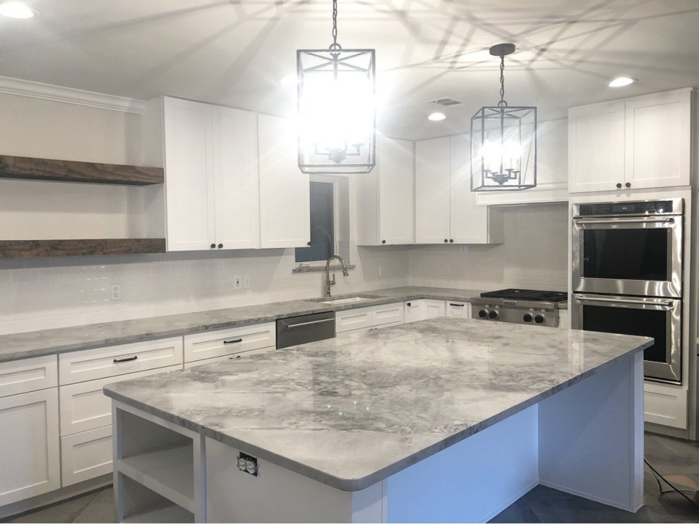 Modern inredning av ett mellanstort grå grått kök, med en enkel diskho, skåp i shakerstil, vita skåp, marmorbänkskiva, vitt stänkskydd, stänkskydd i porslinskakel, rostfria vitvaror, klinkergolv i keramik, en köksö och brunt golv