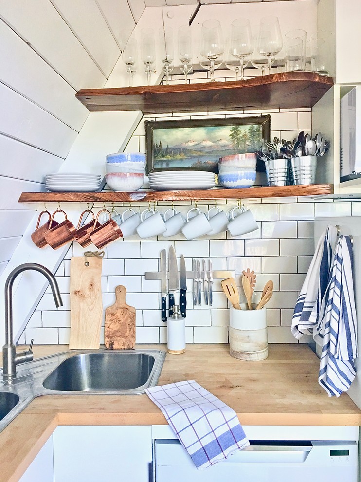 Bild på ett mellanstort rustikt brun brunt kök, med en nedsänkt diskho, släta luckor, vita skåp, träbänkskiva, vitt stänkskydd, stänkskydd i keramik, vita vitvaror, laminatgolv och brunt golv