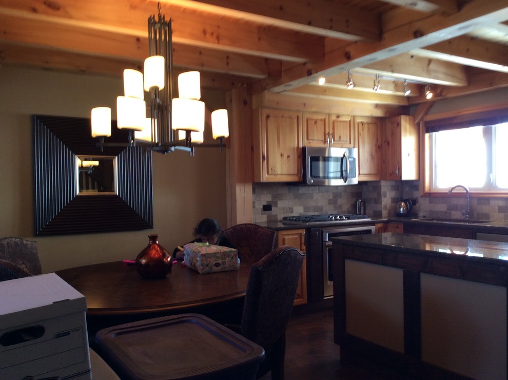 Mid-sized mountain style l-shaped dark wood floor and brown floor eat-in kitchen photo with an undermount sink, raised-panel cabinets, medium tone wood cabinets, granite countertops, gray backsplash, stone tile backsplash, stainless steel appliances and an island