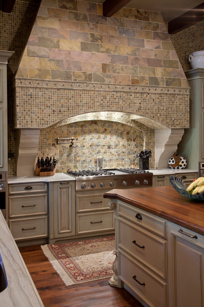 Design ideas for a mediterranean eat-in kitchen in Tampa with wood benchtops, multi-coloured splashback, raised-panel cabinets, beige cabinets and panelled appliances.