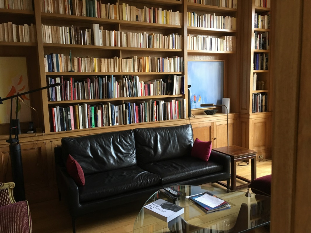 Foto de sala de estar con biblioteca clásica renovada grande con suelo de madera clara y televisor retractable