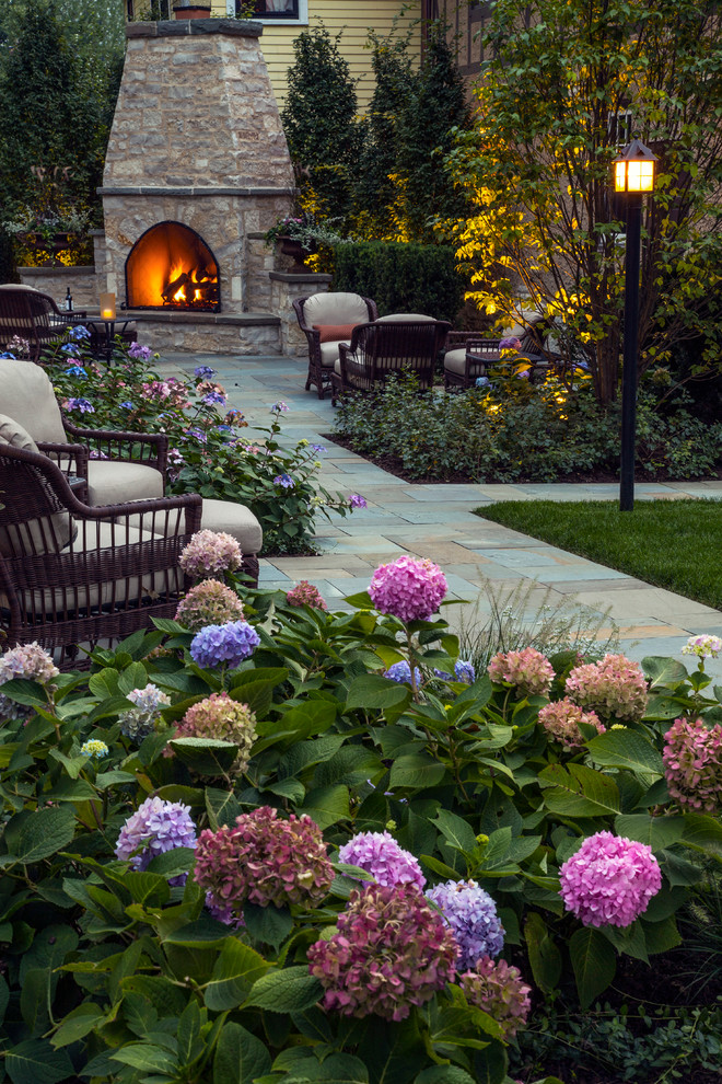 Inspiration for a large traditional backyard partial sun formal garden in Chicago with natural stone pavers and with fireplace.