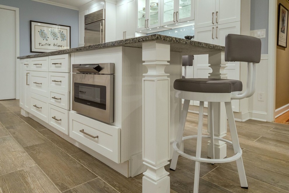 Eat-in kitchen - mid-sized transitional u-shaped porcelain tile eat-in kitchen idea in Orange County with an undermount sink, shaker cabinets, white cabinets, granite countertops, blue backsplash, glass tile backsplash, stainless steel appliances and an island