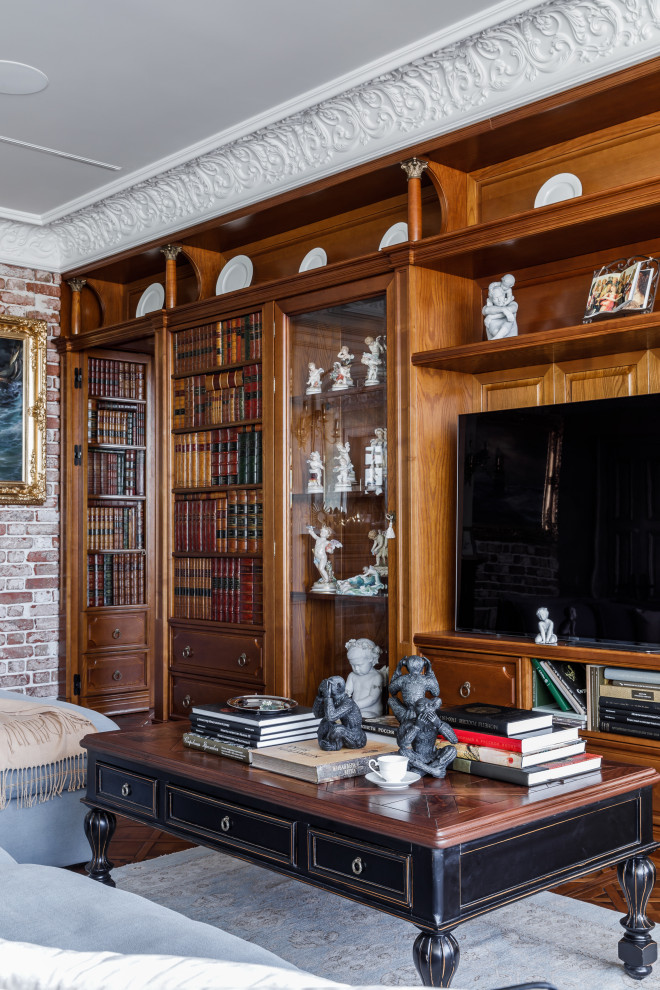 Photo of a large traditional enclosed living room in Other with a library, green walls, dark hardwood floors, a freestanding tv, brown floor and brick walls.