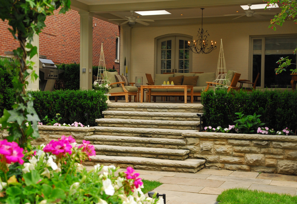 This is an example of a mid-sized traditional backyard partial sun garden for spring in Toronto with a retaining wall and natural stone pavers.