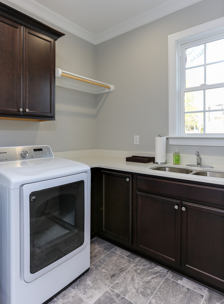 Mid-sized transitional l-shaped utility room in Raleigh with an undermount sink, raised-panel cabinets, dark wood cabinets, quartz benchtops, grey walls, ceramic floors and a side-by-side washer and dryer.