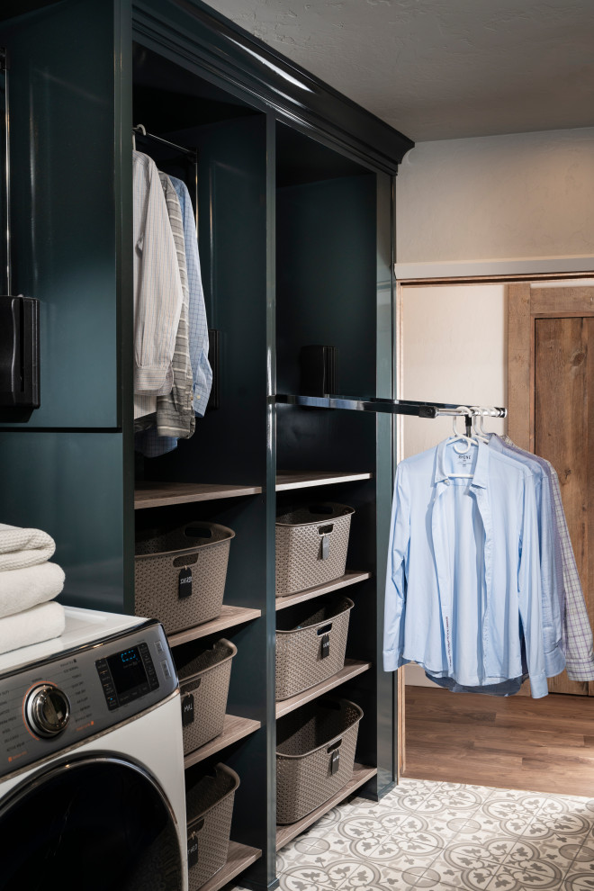 Photo of a mid-sized transitional galley dedicated laundry room in Other with an undermount sink, shaker cabinets, blue cabinets, white walls, porcelain floors, a side-by-side washer and dryer, grey floor and white benchtop.