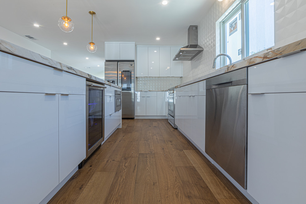 This is an example of a contemporary eat-in kitchen in San Francisco with an undermount sink, flat-panel cabinets, white cabinets, marble benchtops, white splashback, mosaic tile splashback, white appliances, painted wood floors, with island, beige floor and multi-coloured benchtop.
