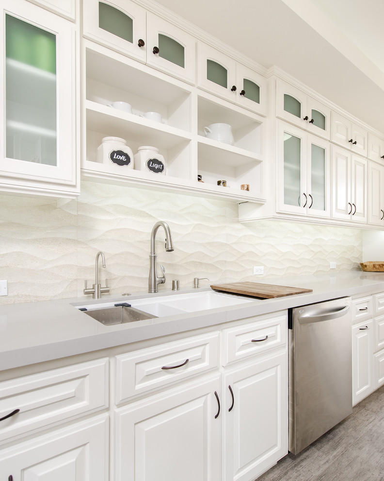 Design ideas for a small traditional galley separate kitchen in Los Angeles with an undermount sink, glass-front cabinets, white cabinets, quartz benchtops, beige splashback, ceramic splashback, stainless steel appliances and porcelain floors.