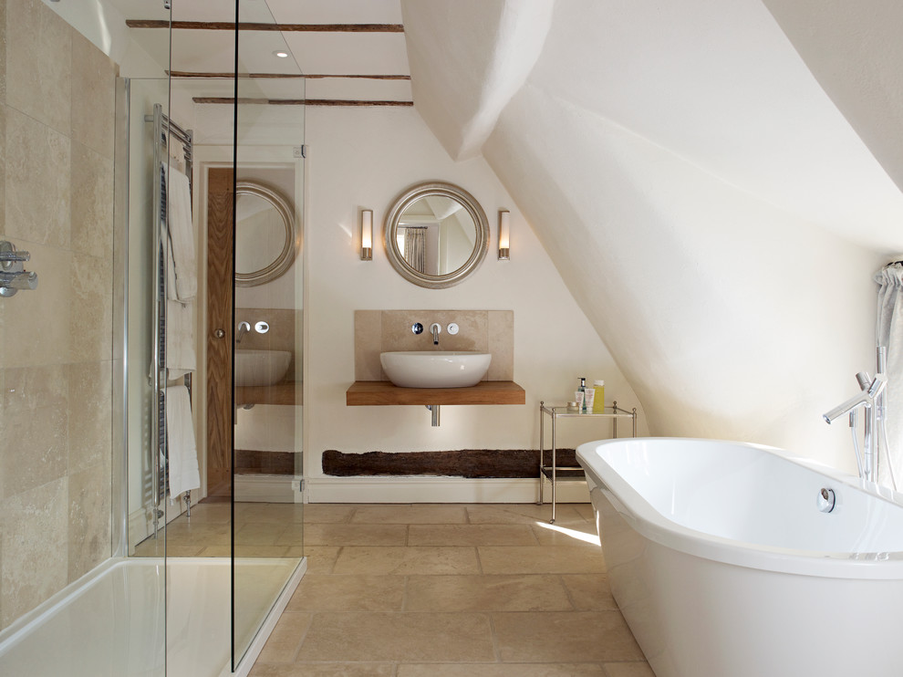 This is an example of a contemporary bathroom in West Midlands with a vessel sink, open cabinets, wood benchtops, a freestanding tub, a corner shower, beige tile, white walls and brown benchtops.