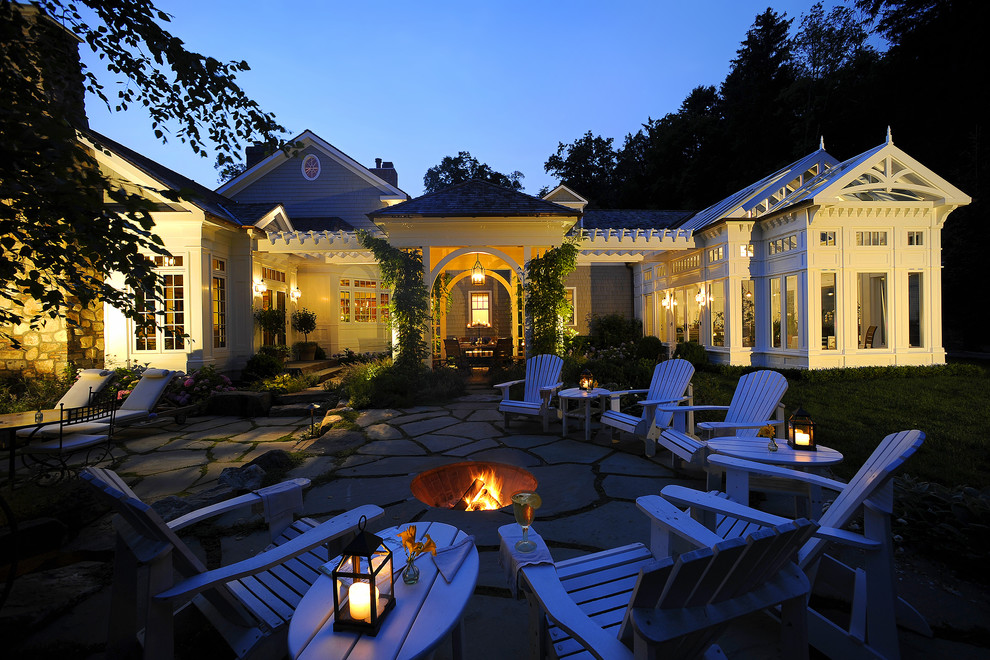 This is an example of a traditional backyard patio in New York with a fire feature, natural stone pavers and a gazebo/cabana.