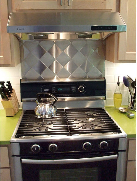 Eat-in kitchen - small galley ceramic tile eat-in kitchen idea in Boston with an undermount sink, shaker cabinets, light wood cabinets, solid surface countertops, metallic backsplash, metal backsplash, stainless steel appliances and a peninsula