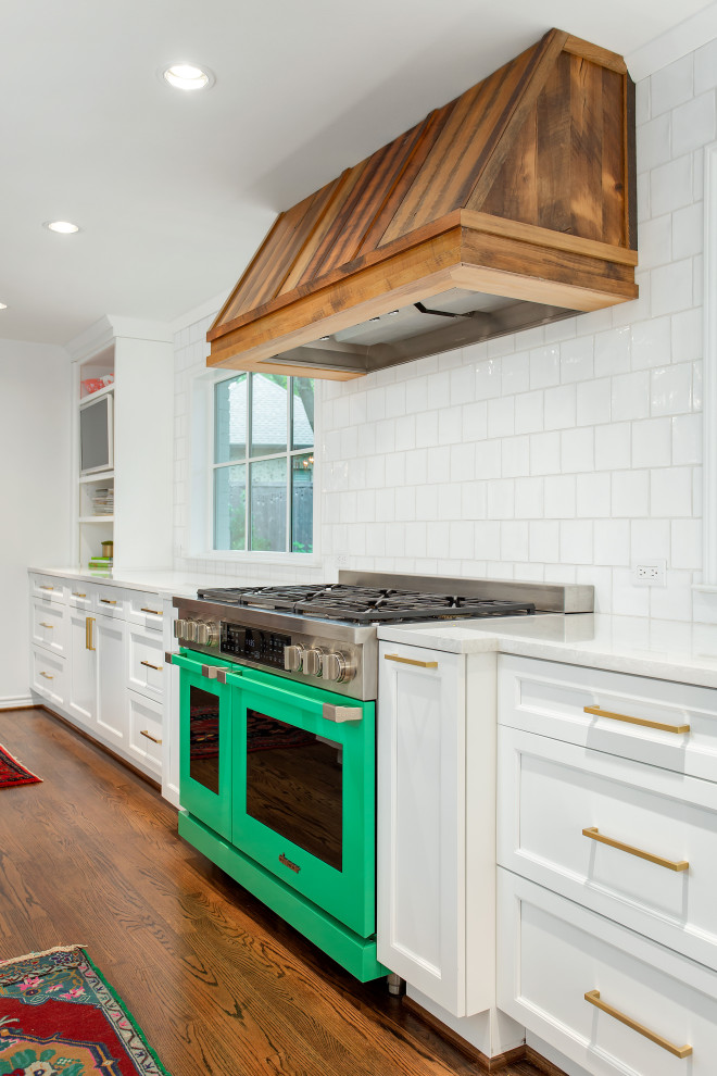 Shabby chic-inspirerad inredning av ett stort vit vitt kök, med en undermonterad diskho, luckor med infälld panel, vita skåp, bänkskiva i kvarts, vitt stänkskydd, stänkskydd i keramik, färgglada vitvaror, mellanmörkt trägolv, en köksö och brunt golv