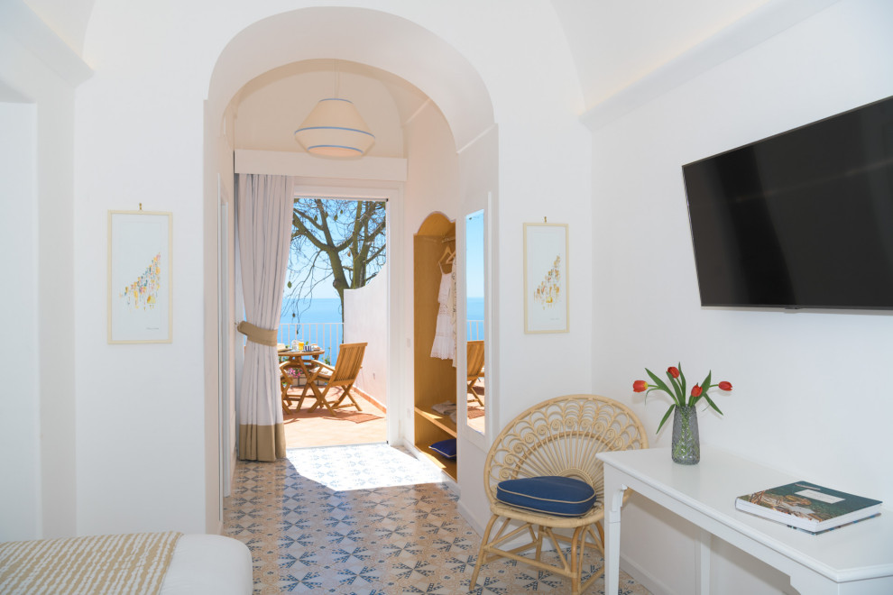 Modelo de dormitorio principal y abovedado mediterráneo de tamaño medio con paredes blancas, suelo de baldosas de cerámica y suelo multicolor