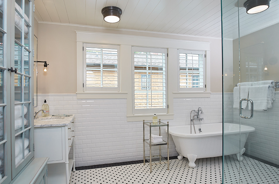 Large transitional master bathroom in Grand Rapids with glass-front cabinets, blue cabinets, a claw-foot tub, an open shower, white tile, ceramic tile, beige walls, porcelain floors, marble benchtops, multi-coloured floor, a hinged shower door, a two-piece toilet, an undermount sink and grey benchtops.