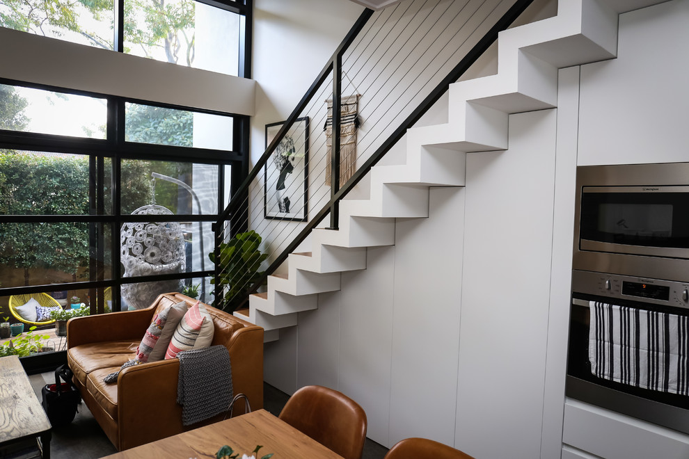 This is an example of a mid-sized contemporary wood l-shaped staircase in Sydney with wood risers and metal railing.