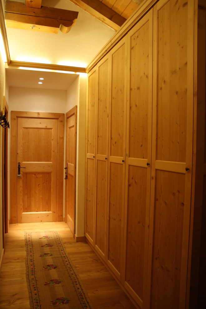 Mid-sized mountain style light wood floor mudroom photo in Milan with white walls and a light wood front door