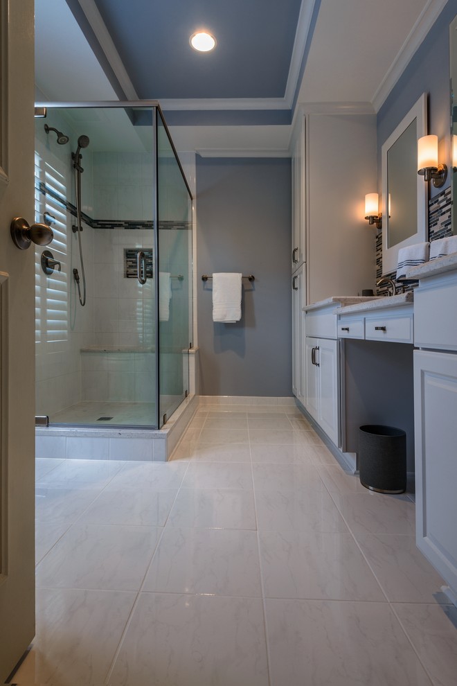 Mid-sized contemporary master bathroom in DC Metro with an undermount sink, white cabinets, solid surface benchtops, a corner shower, a two-piece toilet, white tile, ceramic tile, blue walls and ceramic floors.