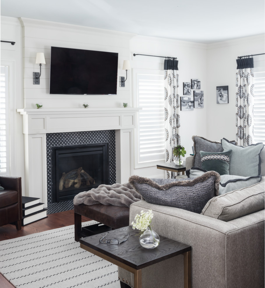 Inspiration for a mid-sized transitional open concept family room in New York with white walls, medium hardwood floors, a standard fireplace, a tile fireplace surround, a wall-mounted tv and brown floor.