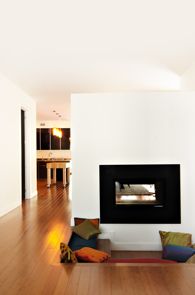 This is an example of a contemporary living room in Ottawa with white walls and a two-sided fireplace.