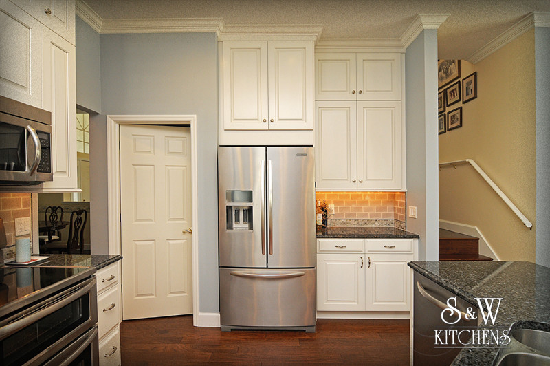 Inspiration for a mid-sized transitional u-shaped dark wood floor open concept kitchen remodel in Orlando with a double-bowl sink, raised-panel cabinets, white cabinets, granite countertops, beige backsplash, subway tile backsplash and stainless steel appliances