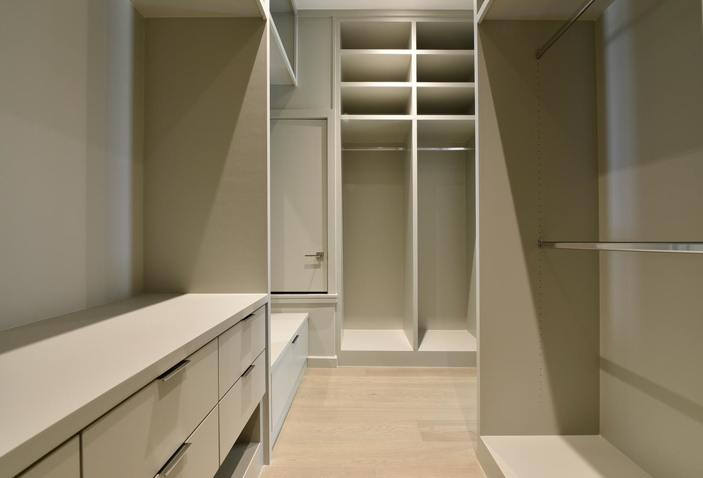 Mid-sized contemporary gender-neutral walk-in wardrobe in Austin with flat-panel cabinets, beige cabinets and light hardwood floors.