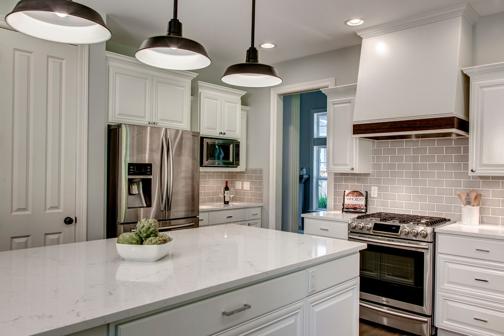 Inspiration for a large transitional u-shaped dark wood floor and brown floor eat-in kitchen remodel in Seattle with an undermount sink, raised-panel cabinets, white cabinets, marble countertops, gray backsplash, ceramic backsplash, stainless steel appliances and an island