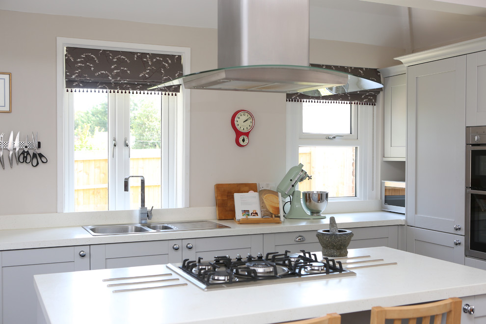 Design ideas for a large transitional l-shaped separate kitchen in Dorset with an integrated sink, shaker cabinets, grey cabinets, solid surface benchtops, white splashback, ceramic splashback, stainless steel appliances, ceramic floors and with island.
