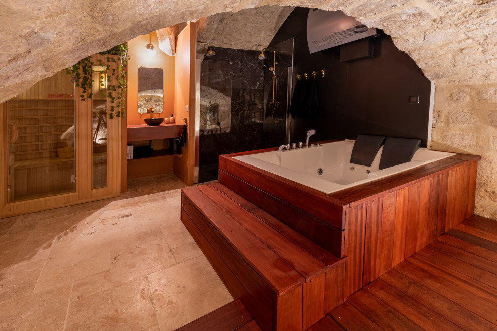 Пример оригинального дизайна: большая главная ванная комната в современном стиле с гидромассажной ванной, душем без бортиков, раздельным унитазом, коричневой плиткой, черными стенами, полом из известняка, накладной раковиной, столешницей из плитки, бежевым полом, душем с распашными дверями, коричневой столешницей, тумбой под одну раковину и сводчатым потолком