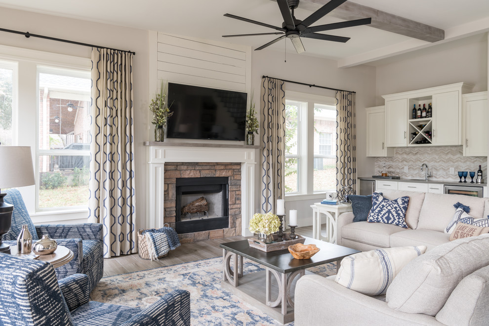 Photo of a large country open concept family room with grey walls, porcelain floors, a standard fireplace, a stone fireplace surround, a wall-mounted tv and grey floor.