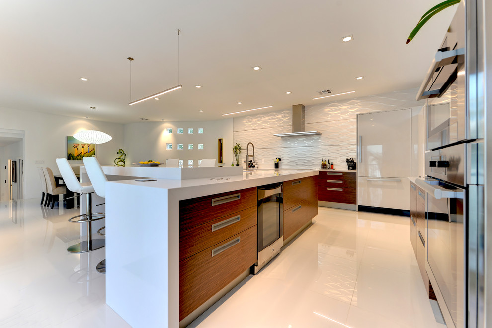Large contemporary l-shaped eat-in kitchen in Other with flat-panel cabinets, medium wood cabinets, solid surface benchtops, white splashback, stainless steel appliances, ceramic floors and a peninsula.