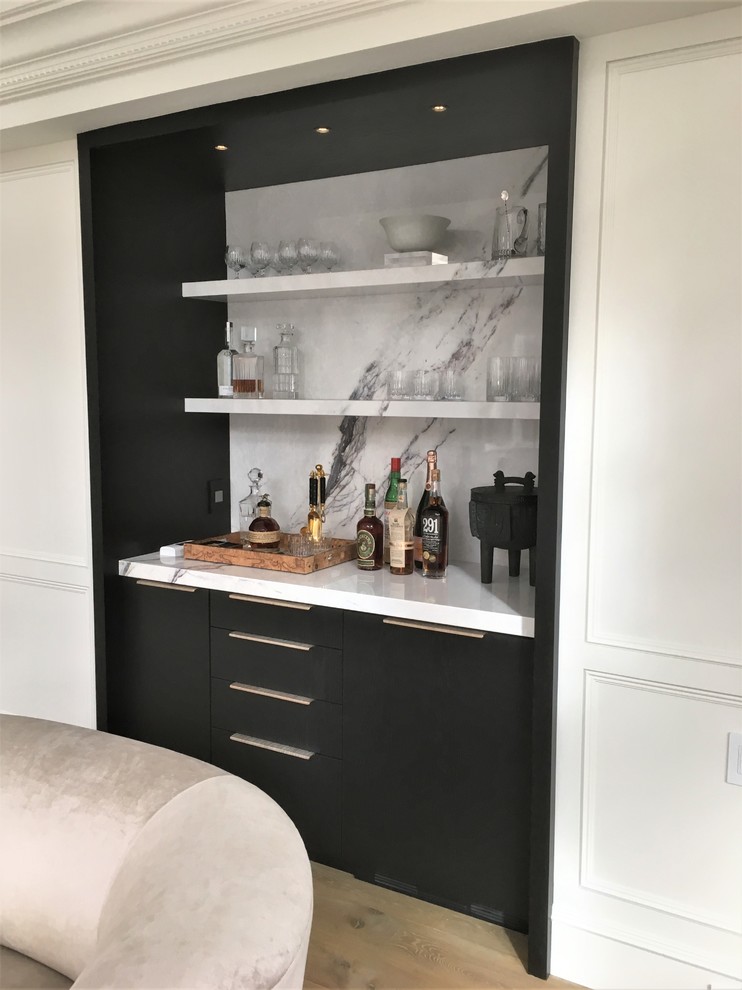 Design ideas for a mid-sized modern galley home bar in Other with no sink, flat-panel cabinets, black cabinets, marble benchtops, white splashback, marble splashback and light hardwood floors.